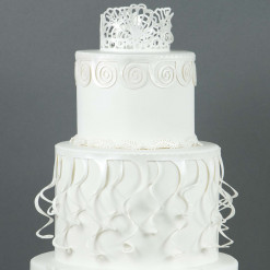 Detail image of lace piece on a white tiered cake.